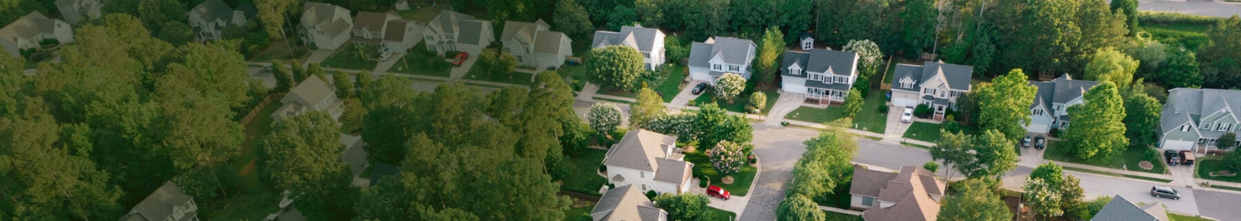Aerial view of suburban single-family homes with manicured lawns, showcasing neighborhood curb appeal and community layout.