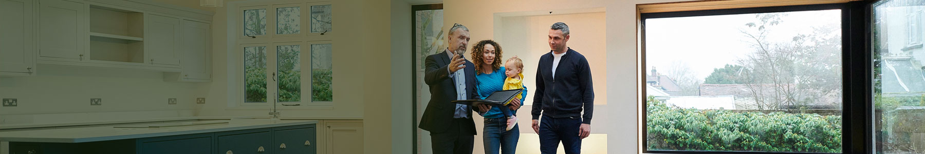 Real estate agent showing a young family a modern home's interior with large windows and open floor plan.