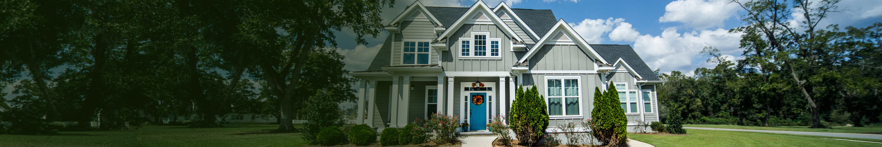 Charming single-family home with lush landscaping, classic architecture, and inviting blue door, perfect for families.
